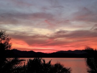 Wall Mural - Sunset River View. Sunset sky. Vibrant beauty from sunset pictured with silhouette of mountain and trees.