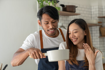 Young Asian couple in apron learning to choose ingredients Ingredients salad dressing in pot, suitable breakfast with salads, vegetables, fruits, available online. lifestyle healthy cooking concept