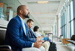 © Nina L/peopleimages.com - Black man, phone and airport in waiting room by window for travel, departure or business trip journey. African American male in wait or flight delay at station for traveling, immigration or airplane