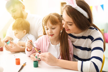 Little girl and her mother painting Easter eggs at home