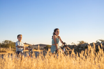 Two kids on a bike in front of a wheat field