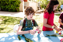 Two Girls At A Table Begin Arranging Flowers To Make A Head Wreath