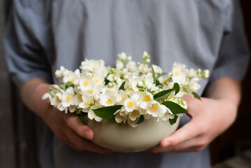 Canvas Print - Man holding a vase with white jasmine flowers	