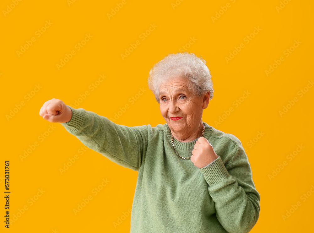 Senior woman in green sweater on yellow background