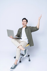 Wall Mural - Young Asian business man sitting on chair and using laptop on background