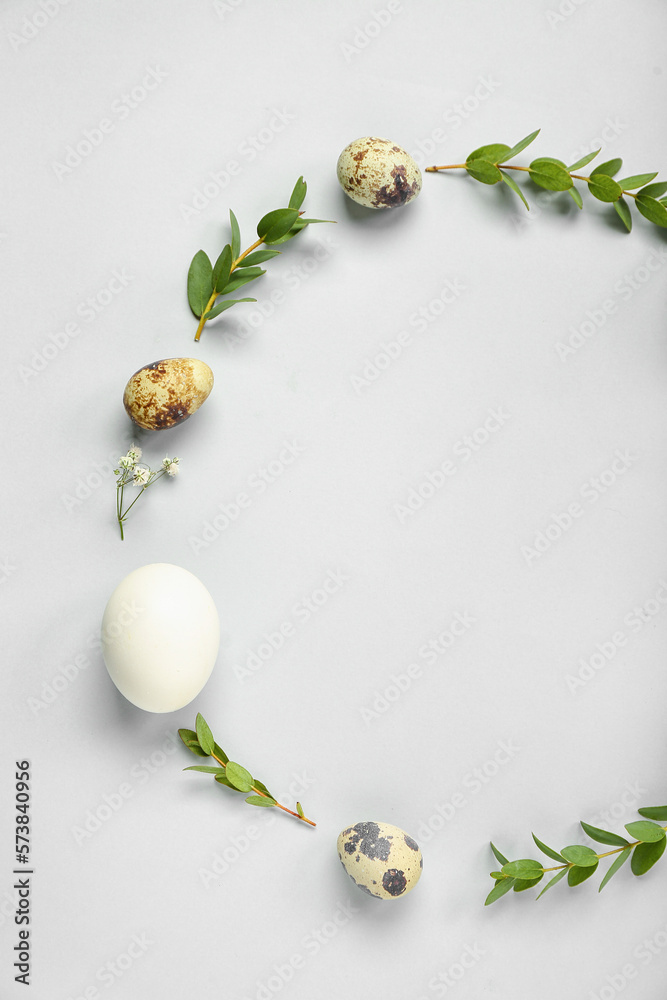Frame made of Easter eggs and eucalyptus branches on grey background