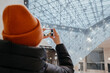 Young woman taking a photo. Inverted pyramid in the shopping mall 'Carrousel du Louvre' with people in Paris, France. Louvre museum hosts one of the biggest art collection in the world.