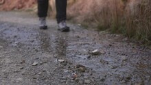 Close Up Of Two Mens Feet Hiking On A Wet Trail Wearing Hiking Boots And Stepping Through Water And Stones.