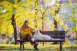 © David - Belgrade, Serbia. November 10th, 2022. Beautiful young woman looking at her cute golden retriever sitting on a park bench on a sunny day.