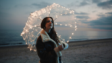 Wall Mural - Glowing umbrella of a girl walking on the beach in the night outdoor