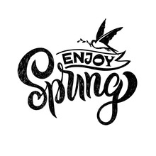 Enjoy Spring. Hand-sketched Lettering Decorated By Ribbon And A Small Spring Bird In Flight With A Branch In Its Beak. Isolated On White. Brush Pen Calligraphy For Tag Template