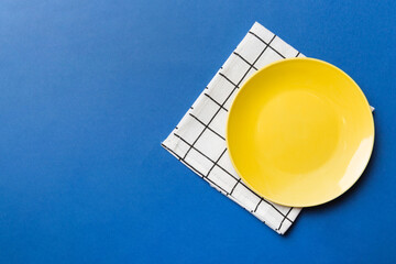 Top view on colored background empty round yellow plate on tablecloth for food. Empty dish on napkin with space for your design