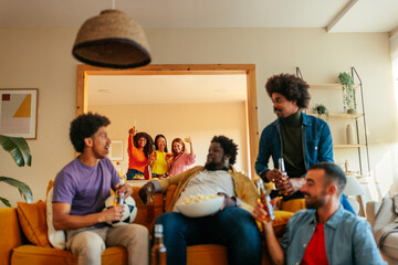 Friends watching soccer game at home.