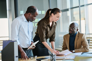 Poster - Young female employee putting paper document on desk of company director negotiating with business partner at working meeting