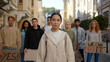 © RZ Images - Students activists at city streets with posters. Asian woman in front. Mass protest concept