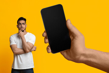 Poster - Doubtful Arab Guy Looking Aside At Blank Smartphone In Huge Female Hand