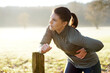 Young woman exercising on a sunny winter morning has pain and side stitch from training and running