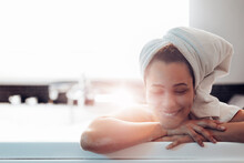 Relaxed Young Lady Leaning On The Edge Of The Bathtub In Warm Light