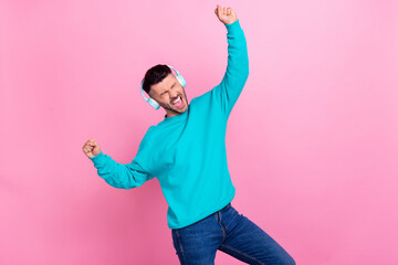 Wall Mural - Portrait of overjoyed cheerful man closed eyes shout scream raise fists listen musis isolated on pink color background