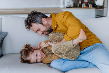 Wall Mural - Father tickling his litttle daughter, having fun.