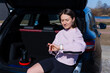© makedonski2015 - A young woman sits in the car after a workout and checks the activity on her smartwatch