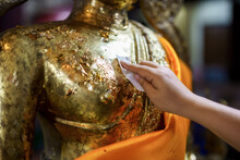 Close-up Asian Woman Tourist Gilding Gold Leaf To Buddha For Worship With Faith To Buddha Statue In Temple Thailand Belief In Buddhism