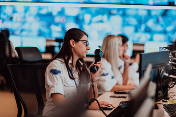 Wall Mural - Group of Security data center operators working in a CCTV monitoring room looking on multiple monitors.Officers Monitoring Multiple Screens for Suspicious Activities