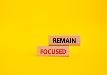 Remain focused symbol. Concept words Remain focused on wooden blocks. Beautiful yellow background. Business and Remain focused concept. Copy space.