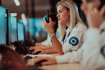 Wall Mural - Group of Security data center operators working in a CCTV monitoring room looking on multiple monitors.Officers Monitoring Multiple Screens for Suspicious Activities