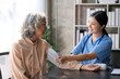 © amnaj - Asian female doctor measuring blood pressure for an elderly female patient.