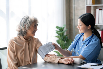 Wall Mural - Asian female doctor measuring blood pressure for an elderly female patient.