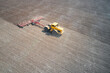 A farmer on a tractor with a harrow prepares the soil for the sowing of crops. Drone footage.
