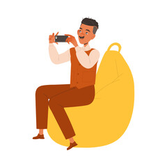 Wall Mural - Mustached Man Character Sitting on Beanbag Chair Filming with Smartphone Working in Coworking Space Vector Illustration