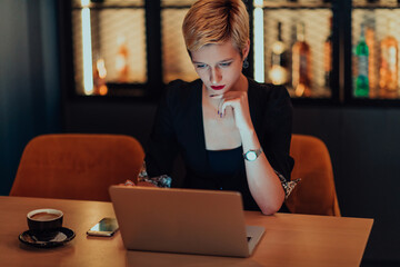 Businesswoman sitting in a cafe while focused on working on a laptop and participating in an online meetings. Selective focus.