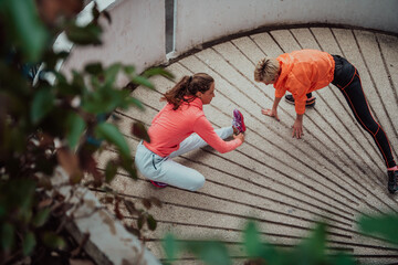 Wall Mural - Two women warming up together and preparing for a morning run in an urban environment. Selective focus 