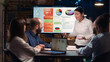 © DC Studio - Project manager presentation, asian company employee explaining analytics research results in business meeting, showing statistics diagrams on digital board. Marketing revenue report visualization