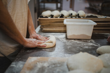 Professional baker preshpaing bread dough during bread making proccess in bakery