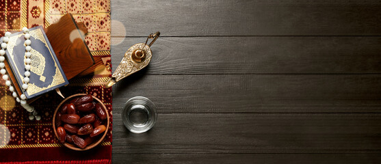 Wall Mural - Dried dates, glass of water, Quran book, prayer beads and Aladdin lamp on dark wooden background with space for text