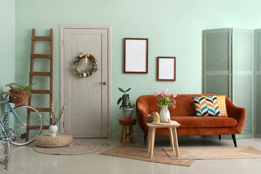 Vase with tulips, Easter bunny and eggs on end table in living room