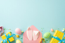 Easter Concept. Top View Photo Of Open Pink Envelope With Bunny Ears Yellow Present Boxes With Blue Bows Colorful Easter Eggs Baking Molds Sprinkles On Isolated Pastel Blue Background With Copyspace