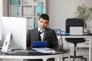 Wall Mural - Tired young accountant working at table in office