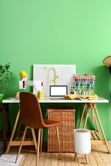 Wall Mural - Tailor's workplace with laptop, sewing machine and organizers near green wall