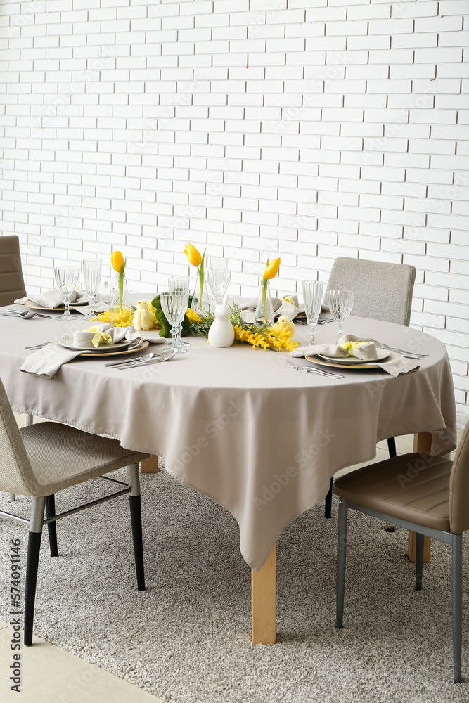 Festive dining table served for Easter celebration near white brick wall