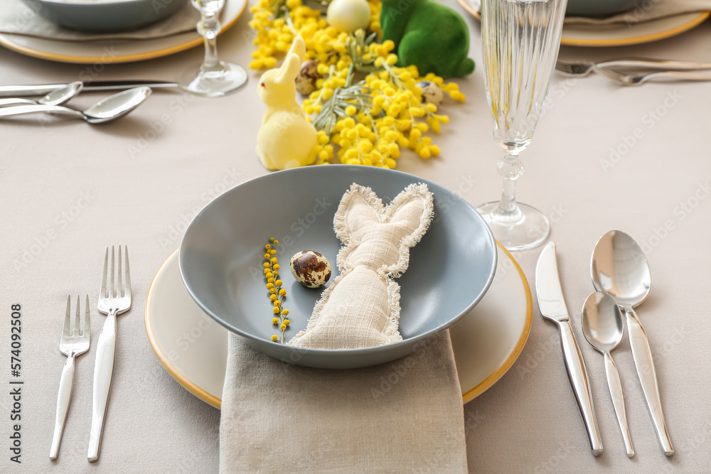 Festive table setting with eggs, bunnies and mimosa flowers served for Easter celebration