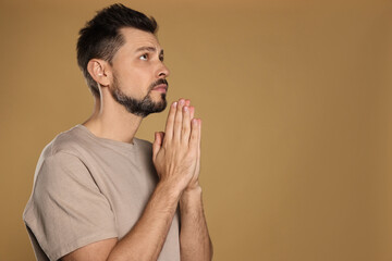 Wall Mural - Man with clasped hands praying on beige background. Space for text