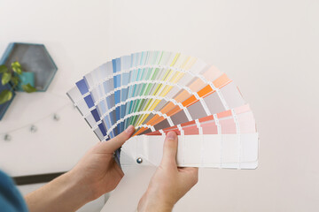 Sticker - Man with palette choosing color for painting wall indoors, closeup. Interior design