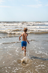 Wall Mural - Youth Child Preteen Boy Running into the Ocean Waves on the Beach