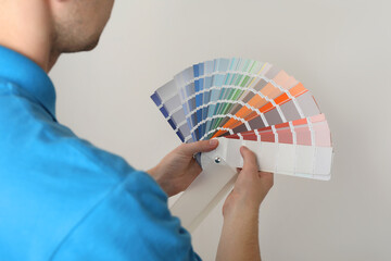 Canvas Print - Man with palette choosing color for painting wall indoors, closeup. Interior design