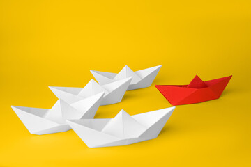 Sticker - Group of paper boats following red one on yellow background. Leadership concept