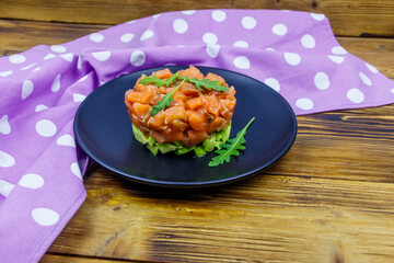 Wall Mural - Salmon tartare with avocado and arugula on wooden table